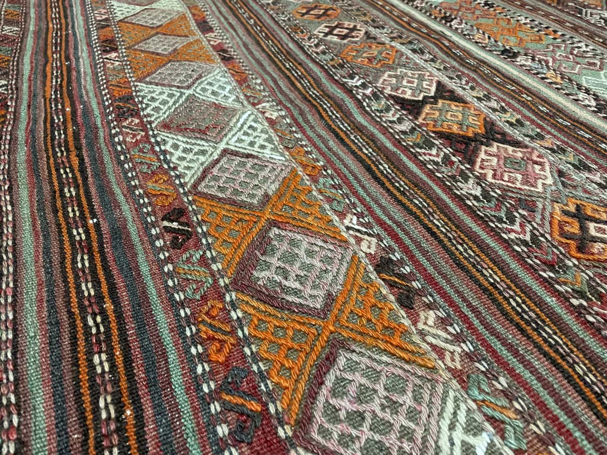 alfombra persa de estilo sumak en dimensiones 154 centímetros de largo por 148 centímetros de ancho con colores principalmente verde y naranja — Primer plano de la textura