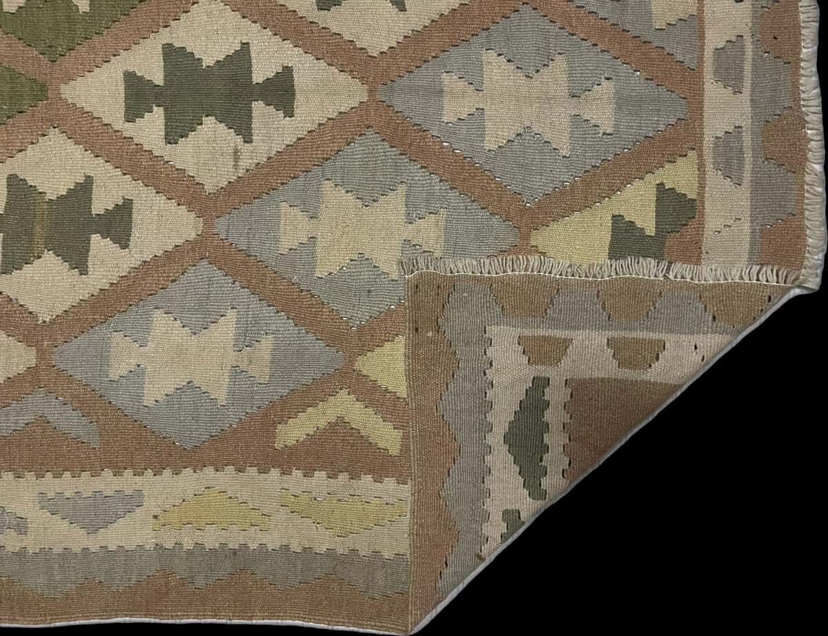 alfombra persa de estilo kilim en dimensiones 225 centímetros de largo por 140 centímetros de ancho con colores principalmente verde y amarillo — Plegada
