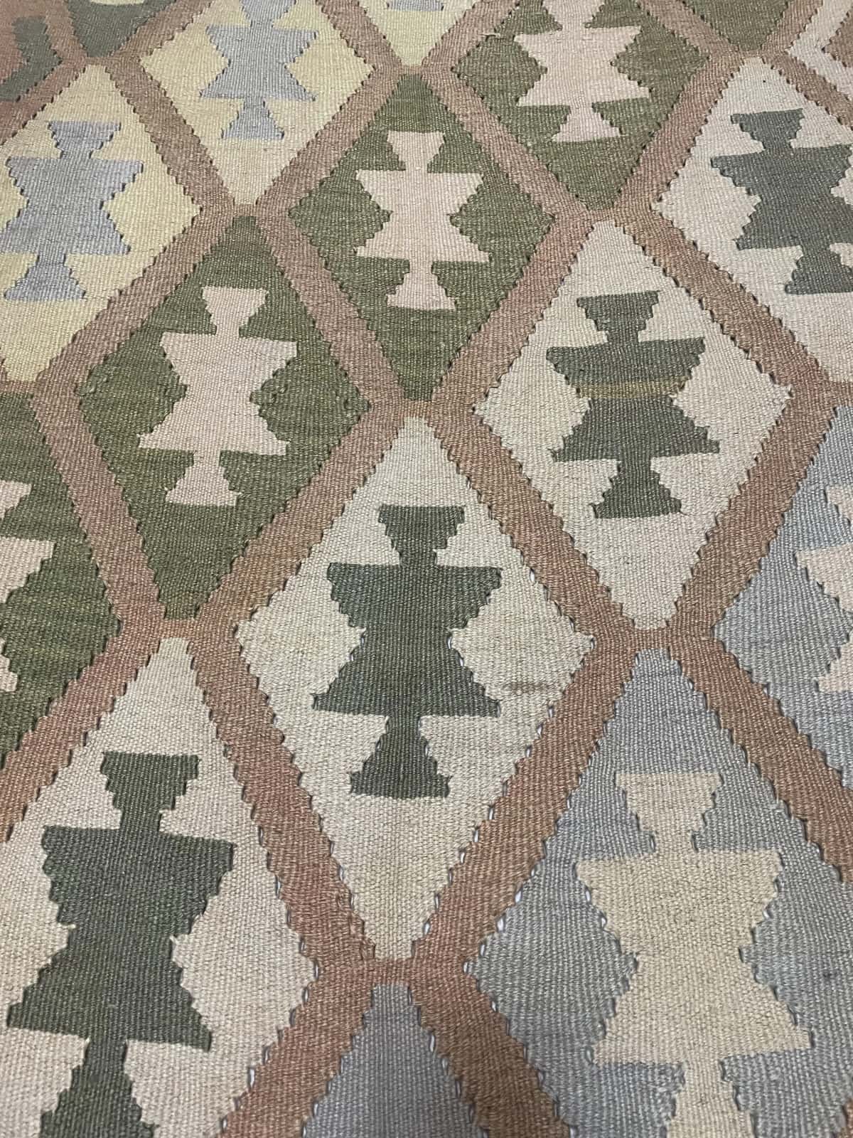 alfombra persa de estilo kilim en dimensiones 225 centímetros de largo por 140 centímetros de ancho con colores principalmente verde y amarillo — Primer plano de la textura