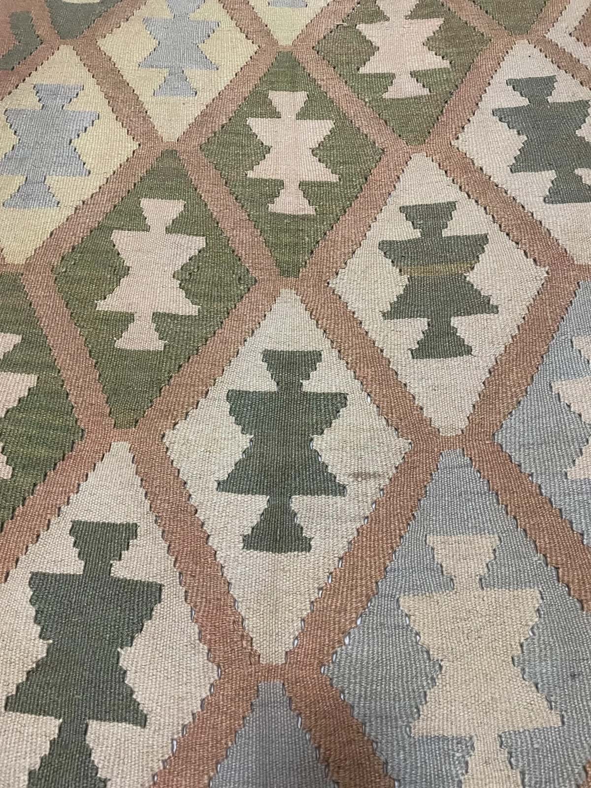 Persian rug of Kilim style in dimensions 225 centimeters length by 140 centimeters width with mainly green and yellow colors — Texture close-up