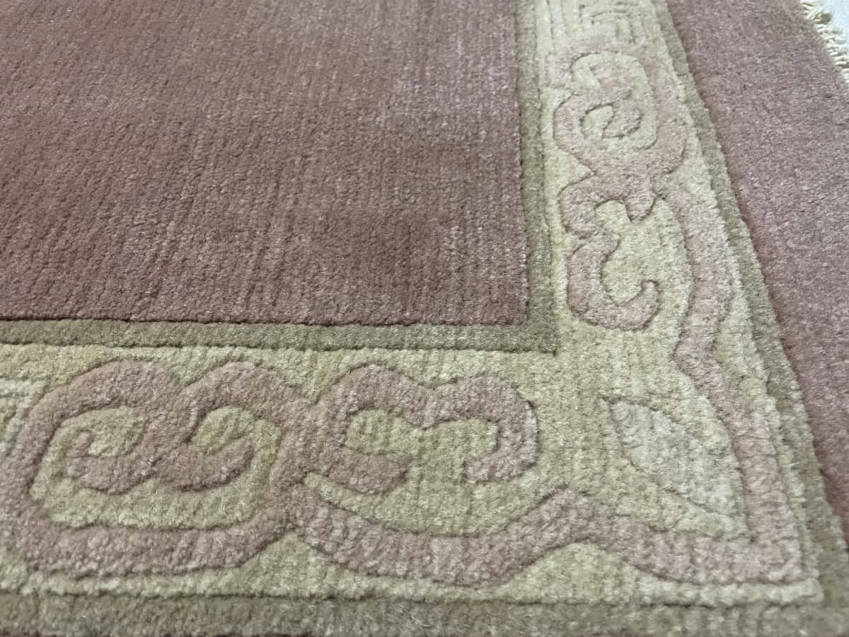 Nepali rug of Tibetan style in dimensions 255 centimeters length by 202 centimeters width with mainly pink colors — Texture close-up