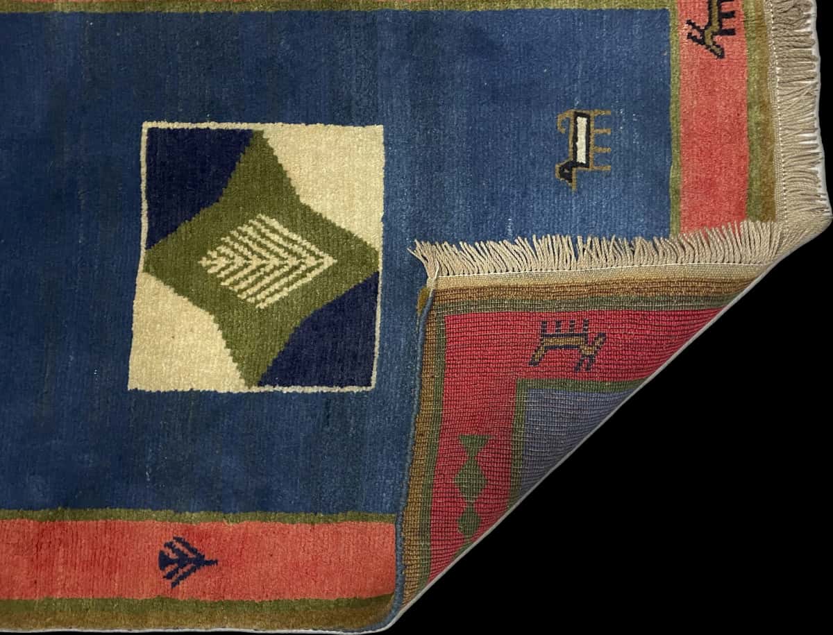 alfombra persa de estilo gabbeh en dimensiones 150 centímetros de largo por 102 centímetros de ancho con colores principalmente verde — Plegada