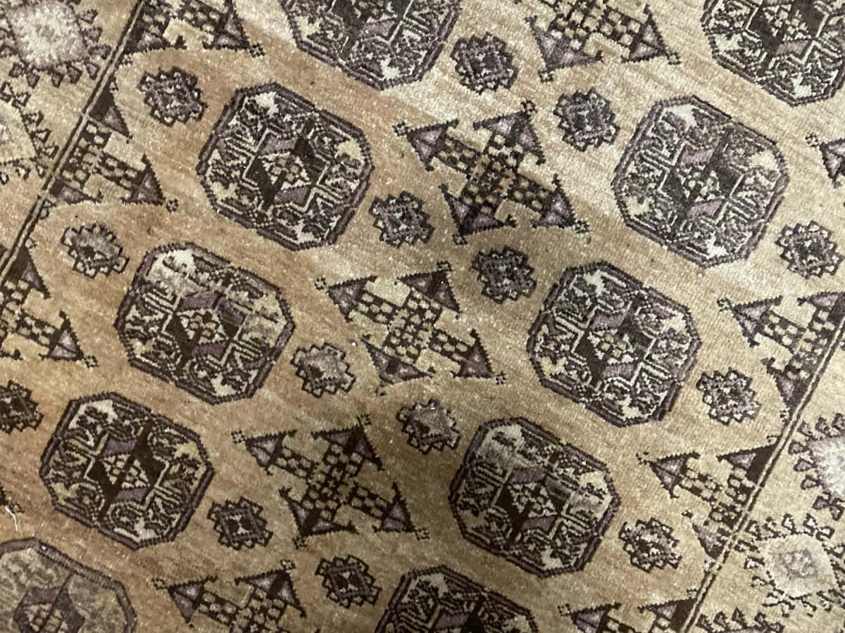 alfombra persa de estilo baluch en dimensiones 204 centímetros de largo por 117 centímetros de ancho con colores principalmente marrón — Primer plano de la textura