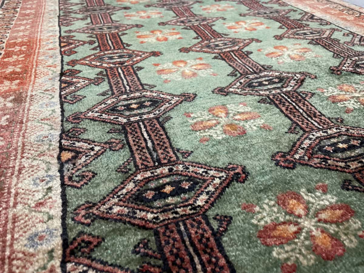 Persian rug of Turkoman style in dimensions 179 centimeters length by 94 centimeters width with mainly green and red colors — Texture close-up