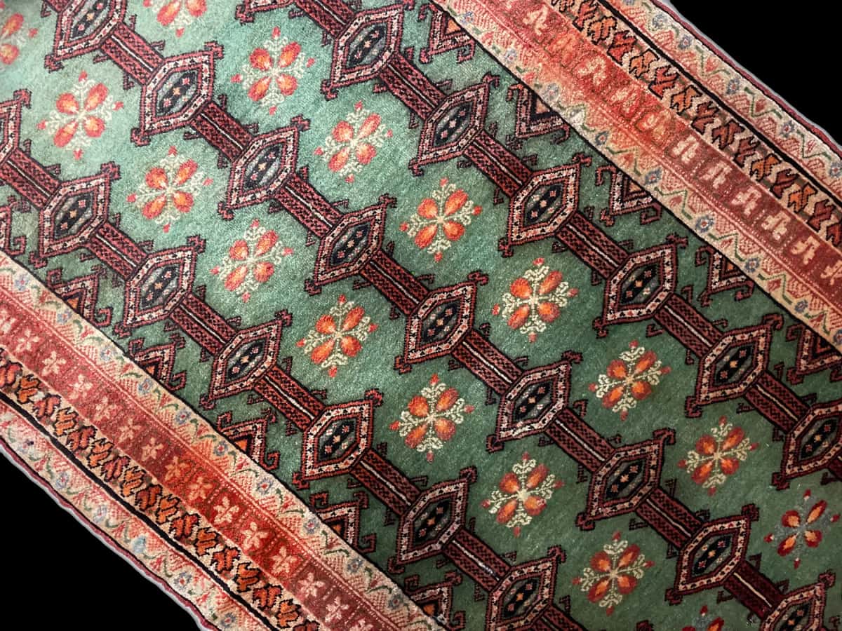 persischer Teppich im turkmenischer Stil in den Maßen 179 Zentimeter Länge mal 94 Zentimeter Breite mit überwiegend grün und rot Farben — Perspektive