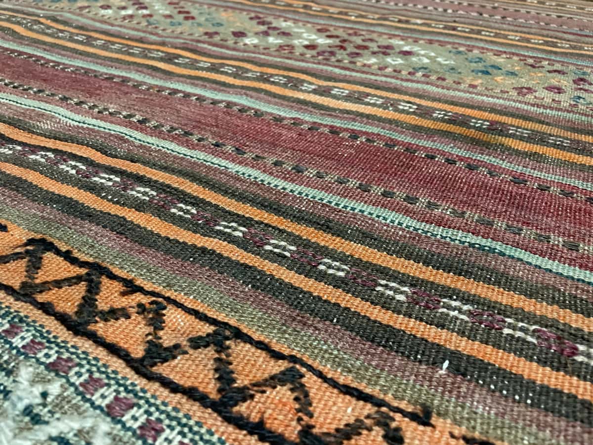 Persian rug of Sumak style in dimensions 129 centimeters length by 123 centimeters width with mainly brown and green colors — Texture close-up