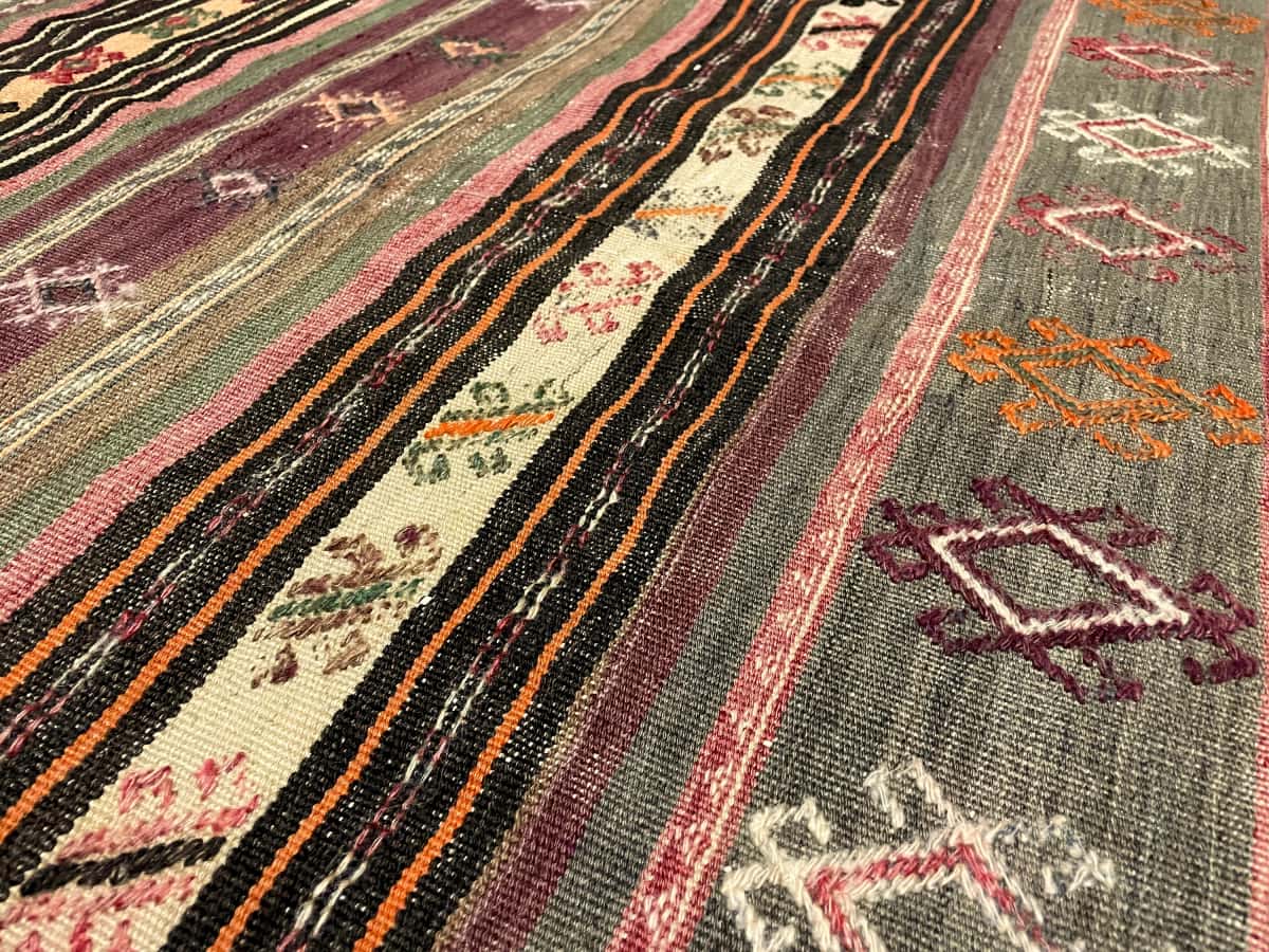 persischer Teppich im Kelim-Sumak Stil in den Maßen 212 Zentimeter Länge mal 146 Zentimeter Breite mit überwiegend Rot und Grün Farben — Nahaufnahme der Textur