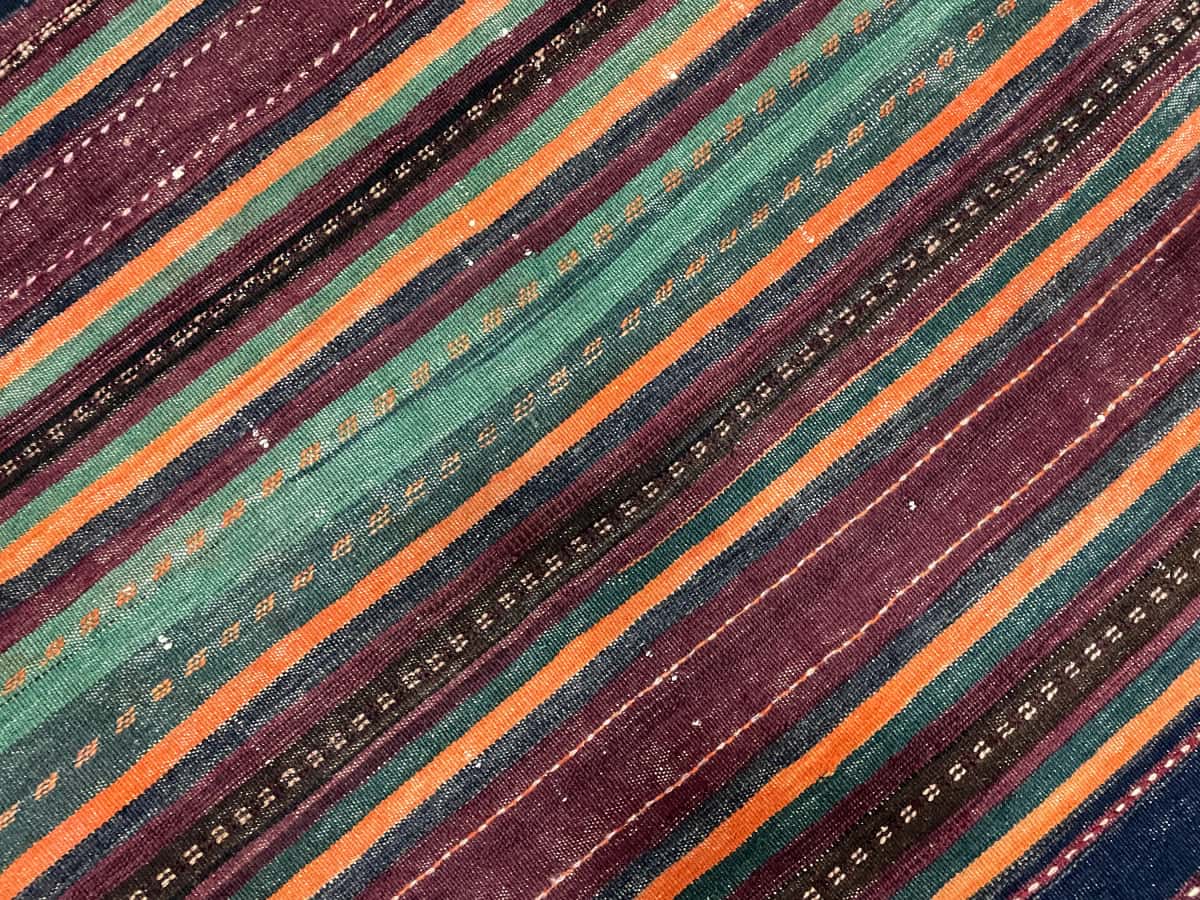 Persian rug of Sumak style in dimensions 152 centimeters length by 135 centimeters width with mainly purple and orange colors — Texture close-up
