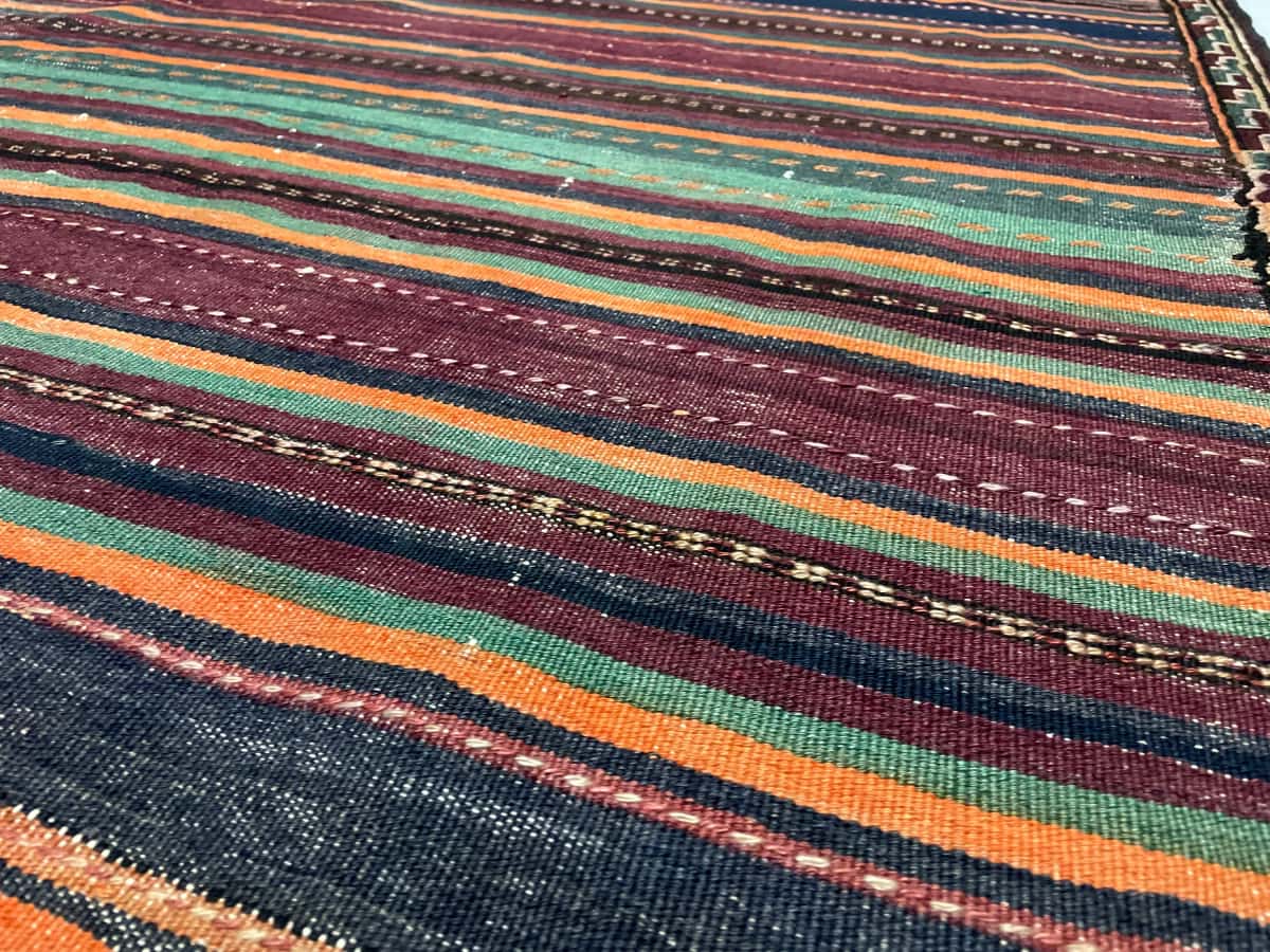 Persian rug of Sumak style in dimensions 152 centimeters length by 135 centimeters width with mainly purple and orange colors — Texture close-up