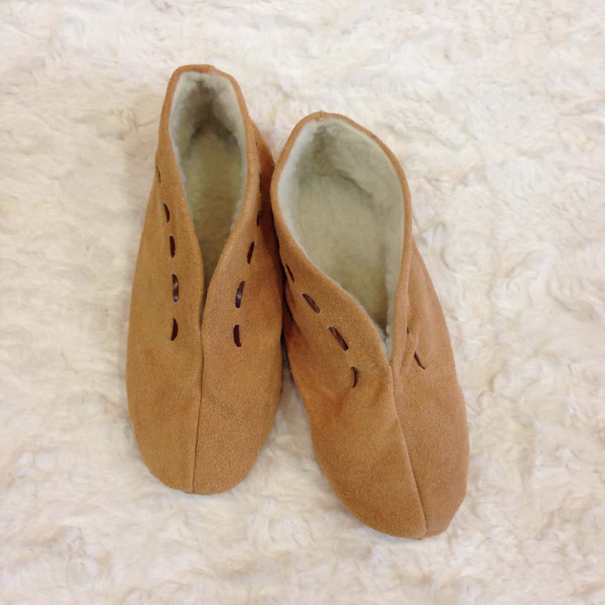 Top-down view of two babucha brown shoes side by side, the interior material can be seen being white plush — Suela