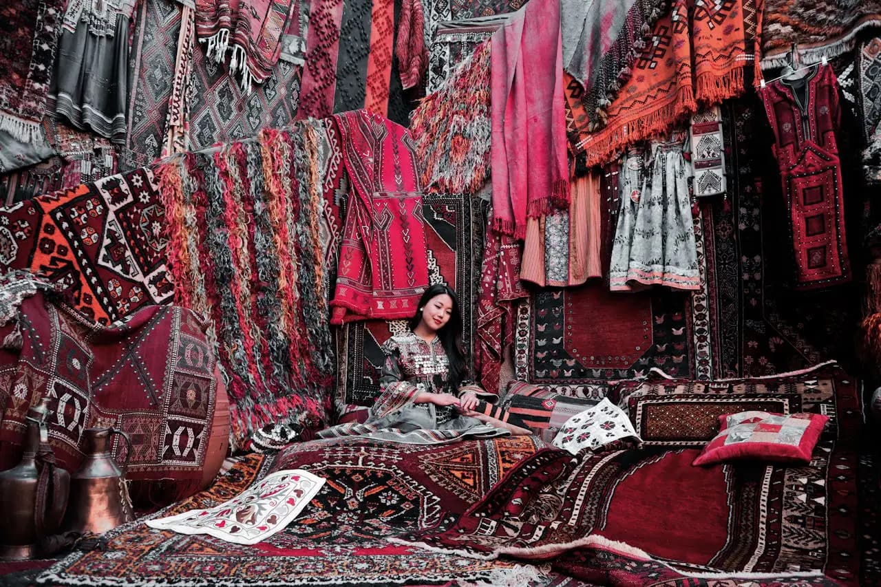 Femme assise sur un tapis, entourée de tapis et d'autres textiles en Turquie