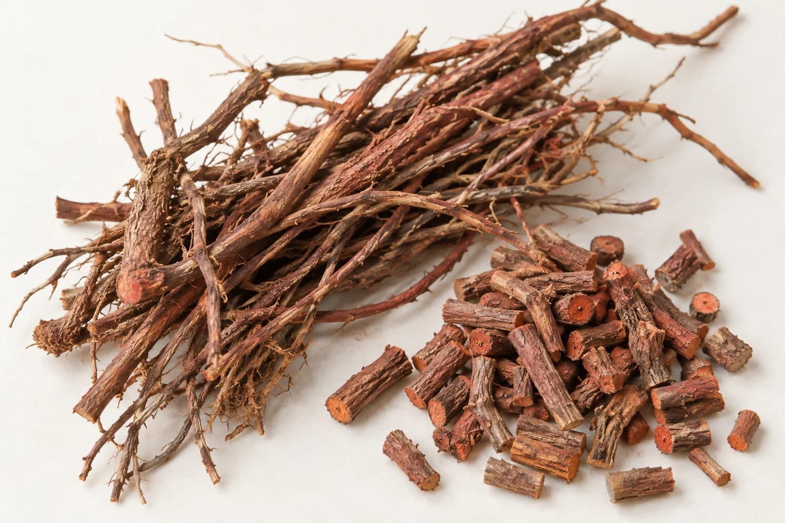 Thin dried madder roots and chopped pieces with orange-red interiors.