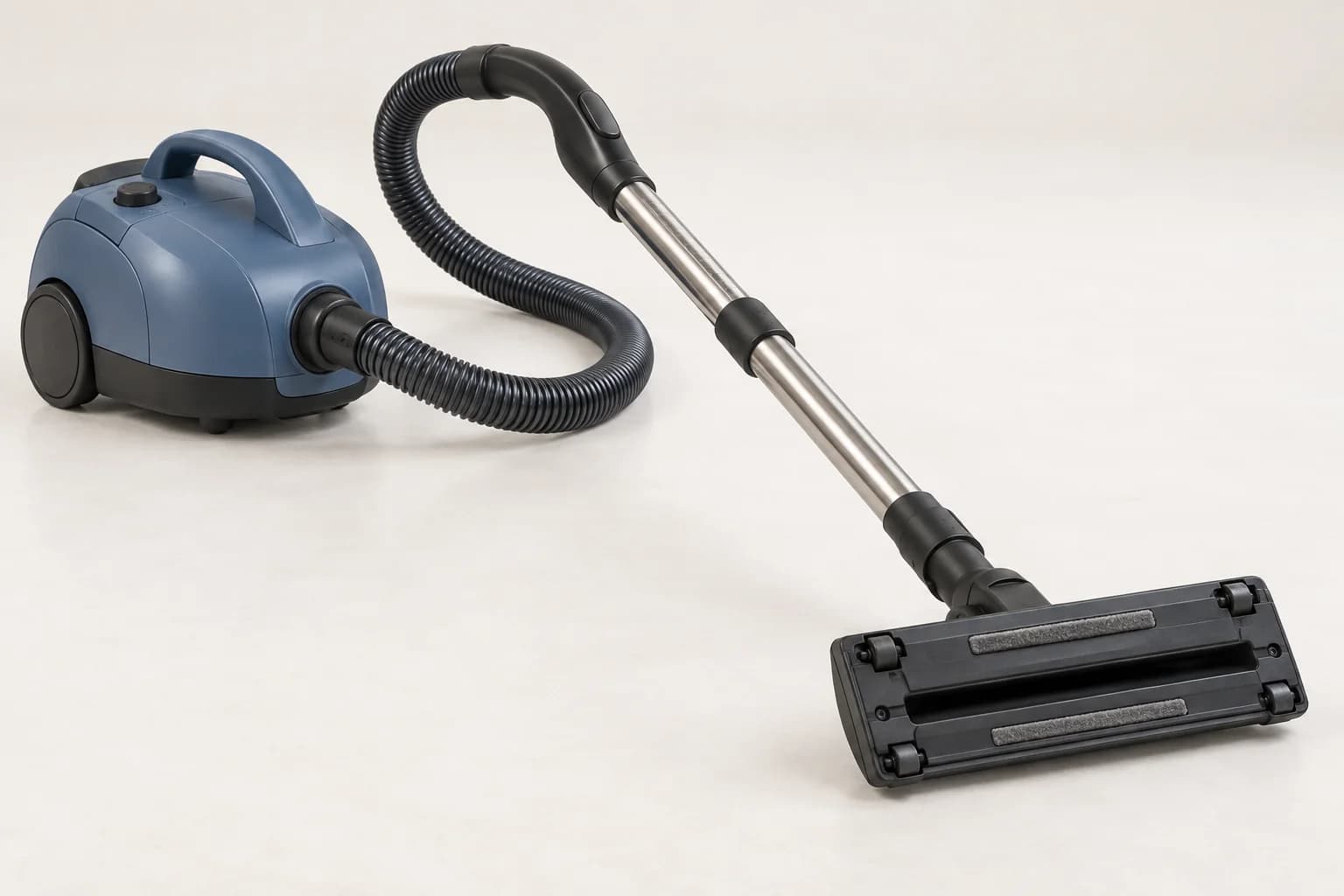 Corps d’aspirateur sur roulettes relié par un flexible et un tube métallique à une tête retournée, dont l’ouverture d’aspiration ne comporte pas de brosse rotative.