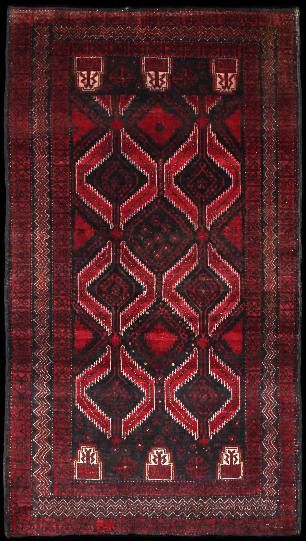 alfombra persa de estilo baluch en dimensiones 184 centímetros de largo por 105 centímetros de ancho con colores principalmente rojo