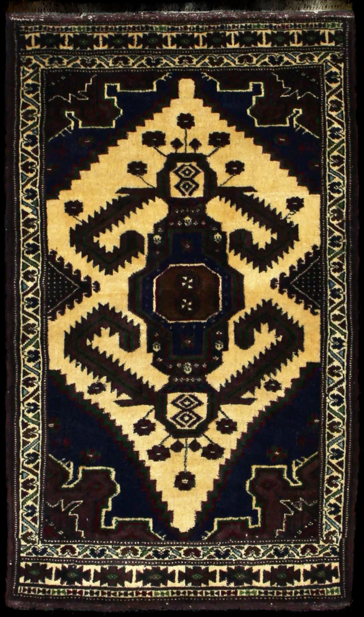 alfombra persa de estilo turcomana en dimensiones 132 centímetros de largo por 78 centímetros de ancho con colores principalmente marrón y amarillo