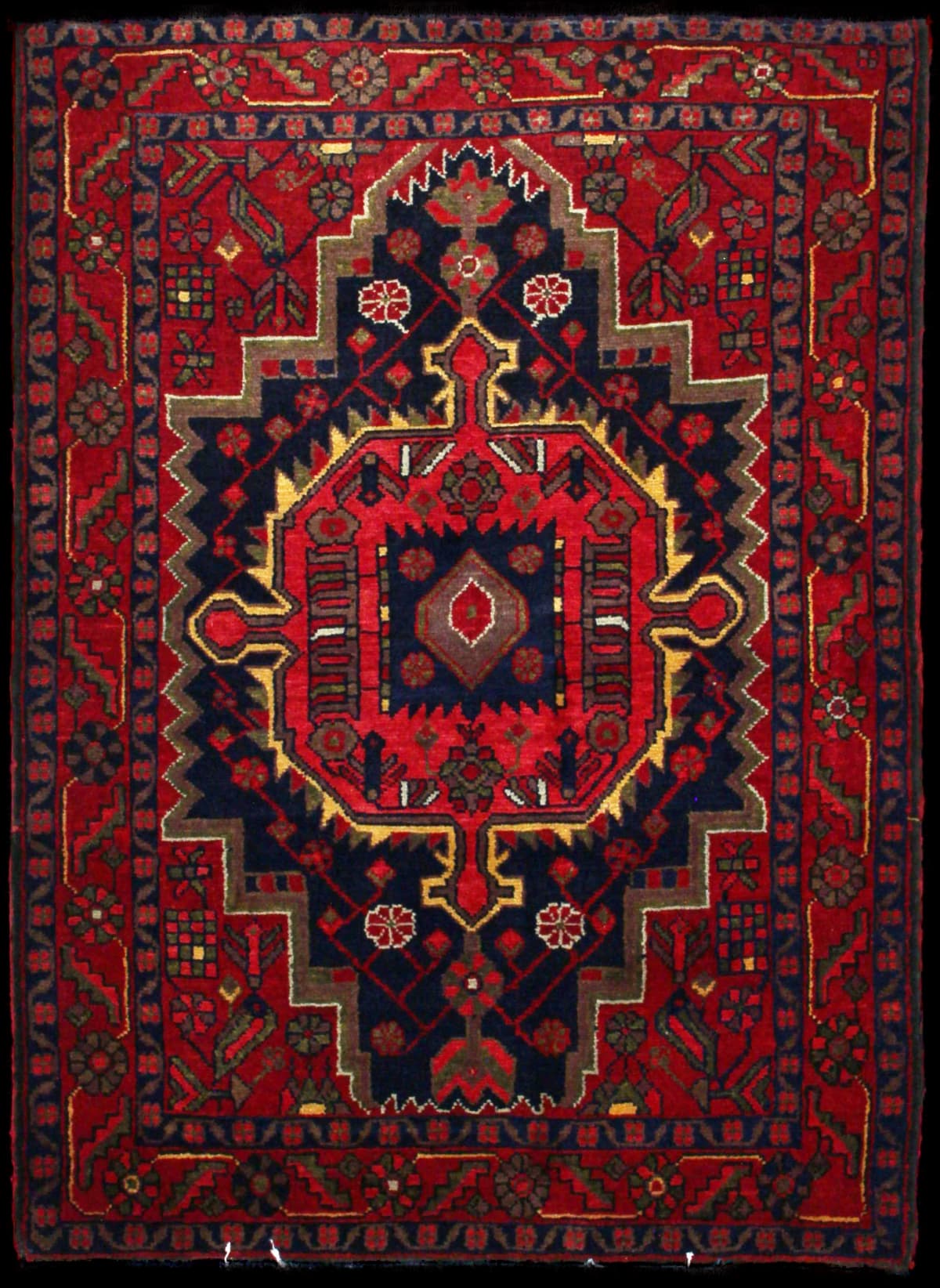 alfombra persa de estilo Nahavand en dimensiones 155 centímetros de largo por 115 centímetros de ancho con colores principalmente rojo