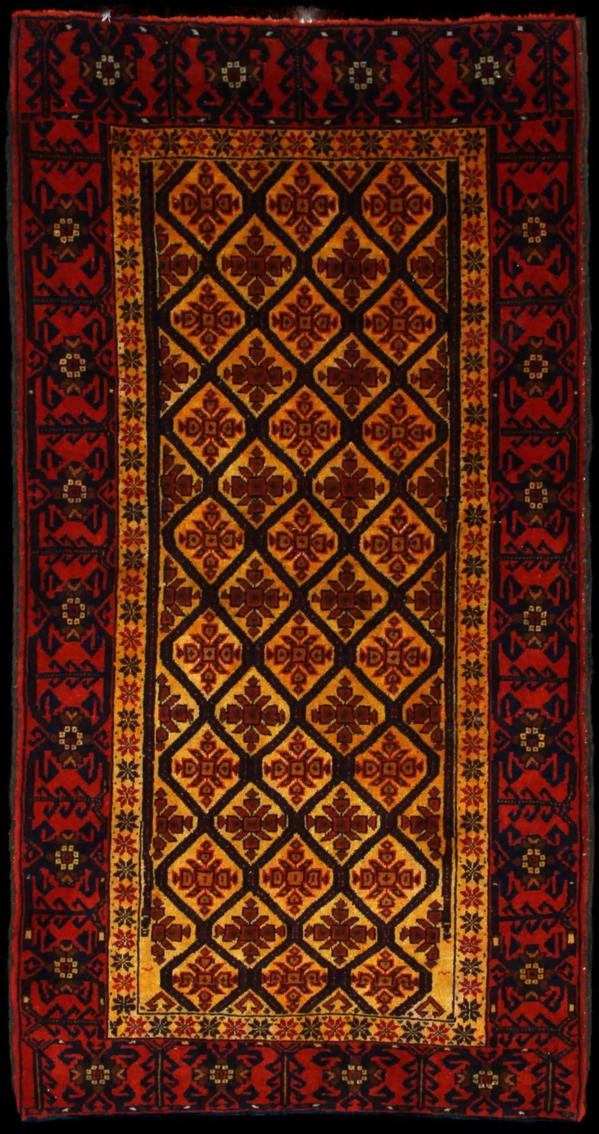 alfombra persa de estilo baluch en dimensiones 176 centímetros de largo por 91 centímetros de ancho con colores principalmente naranja y amarillo