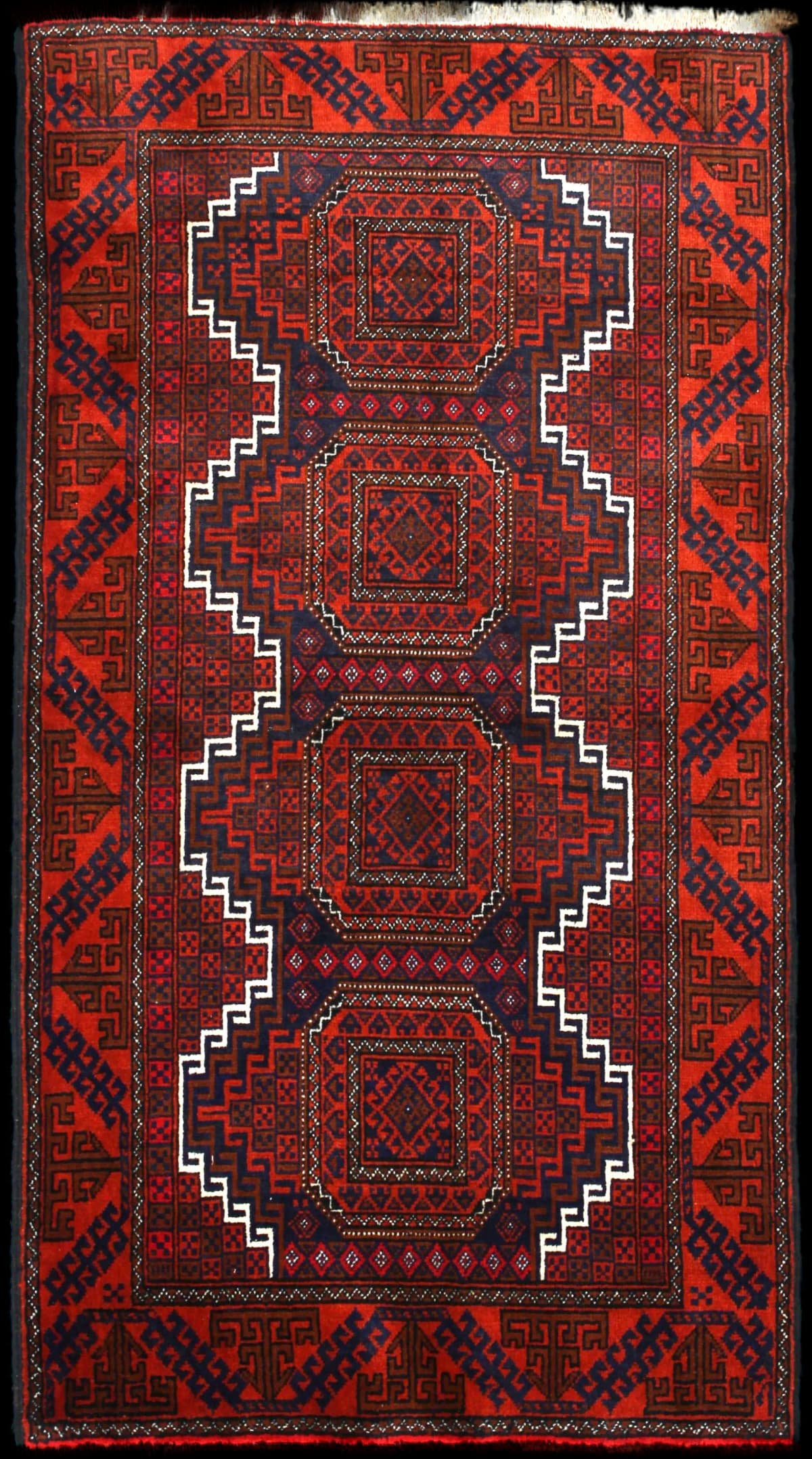 alfombra persa de estilo baluch en dimensiones 180 centímetros de largo por 98 centímetros de ancho con colores principalmente naranja y azul