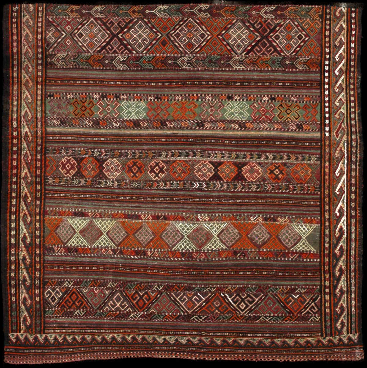 alfombra persa de estilo sumak en dimensiones 154 centímetros de largo por 148 centímetros de ancho con colores principalmente verde y naranja