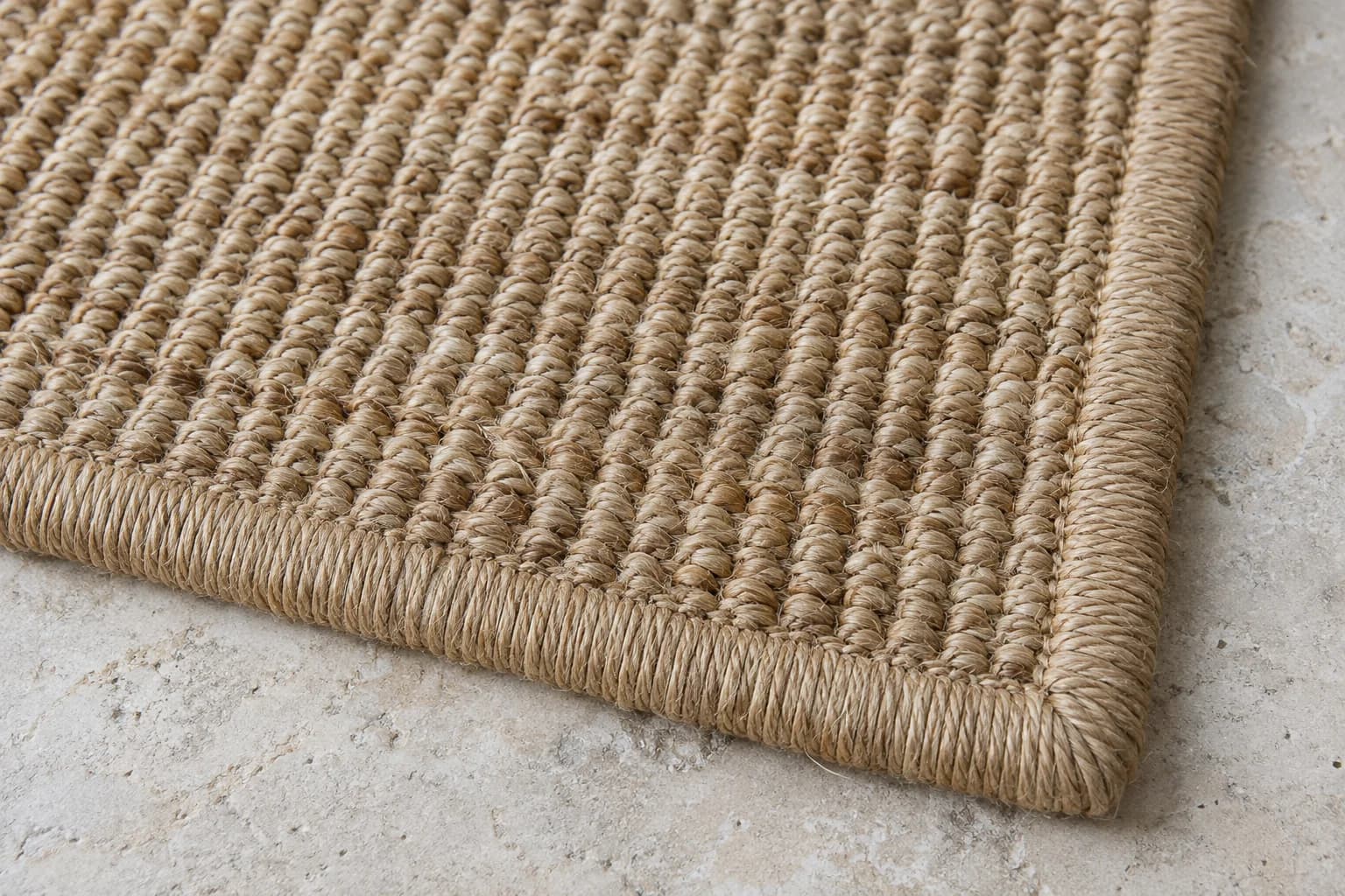 Close-up of a dry sisal rug showing coarse woven plant fibers and its bound edge