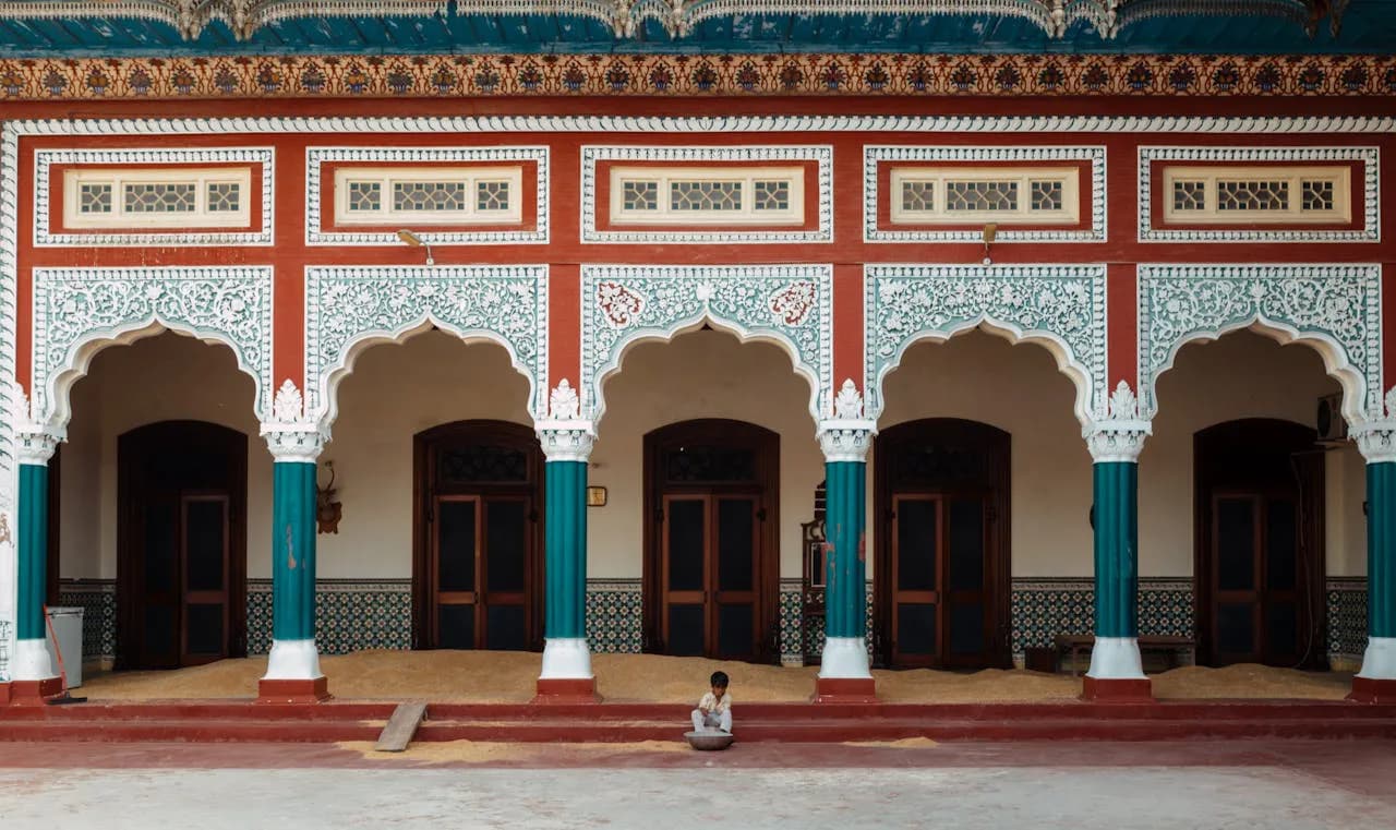 En ung pojke som sitter framför en rikt dekorerad byggnad i Faisalabad, Punjab, Pakistan